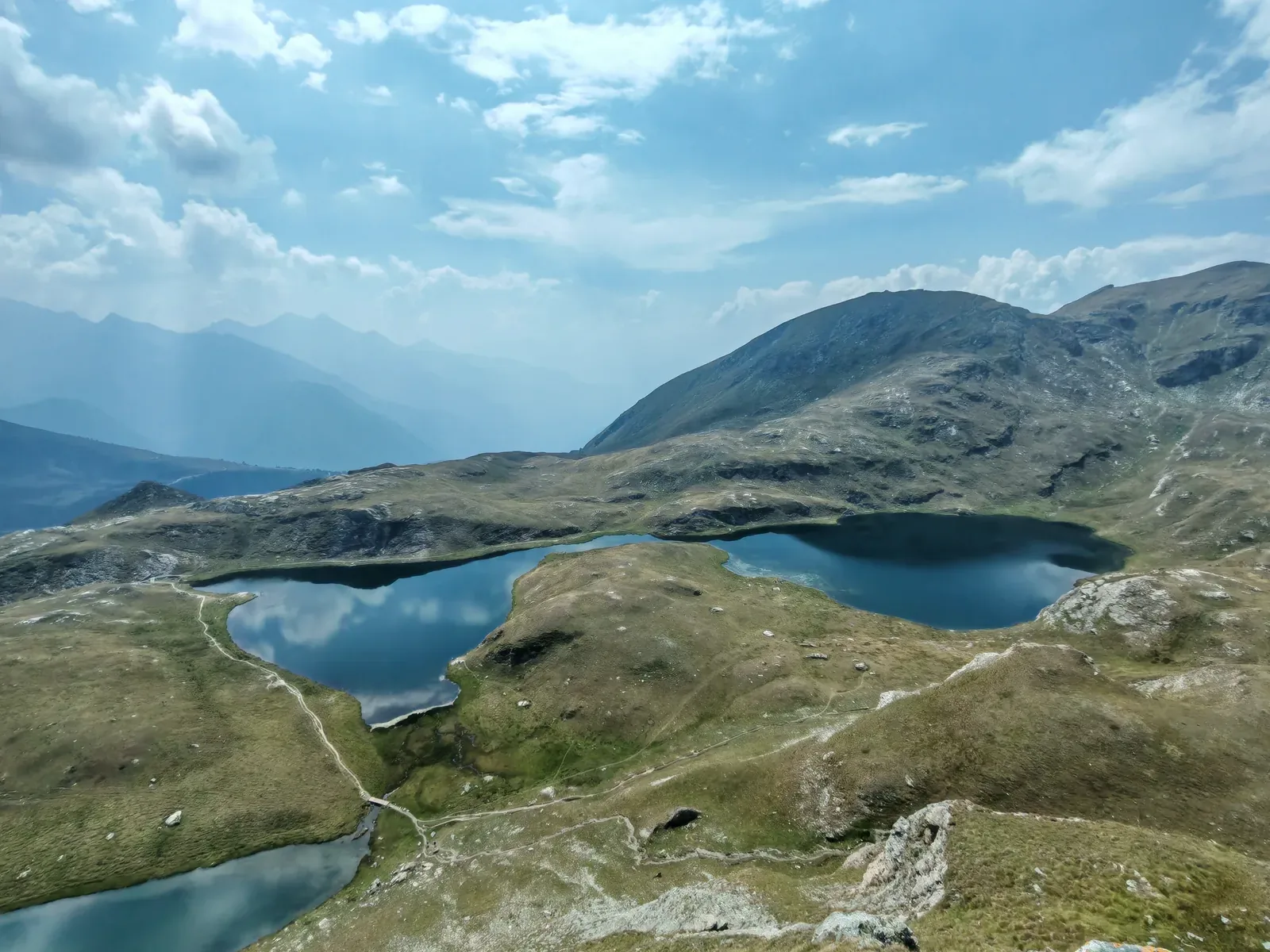Dal dosso panoramico la vista sui laghi Verde e della Battaglia allineati, con la valle che si apre nella foschia